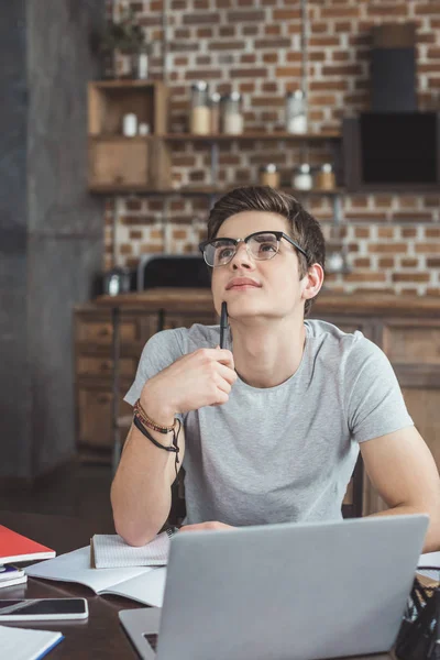 Studente maschio sognante che fa i compiti a casa — Foto stock