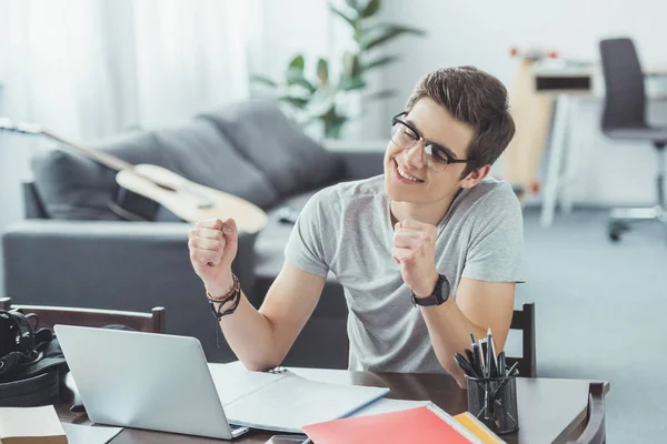 Excited student with laptop doing homework at home — Stock Photo