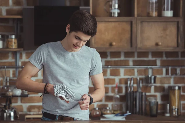 Teenager cleaning dinnerware with towel on kitchen — Stock Photo