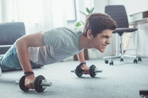 Young boy doing push ups with dumbbells at home — Stock Photo