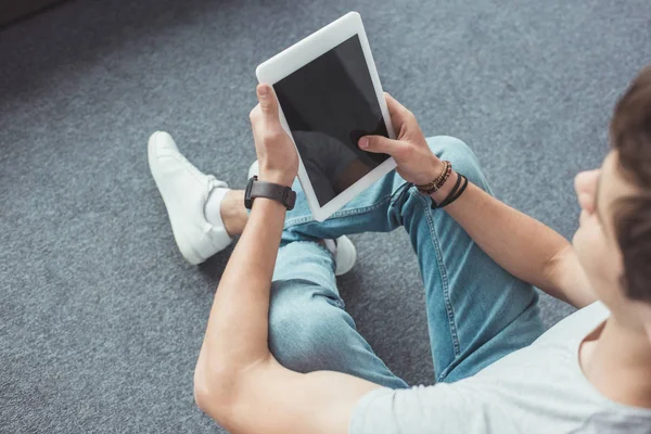 Young man using digital tablet with blank screen while sitting on floor — Stock Photo
