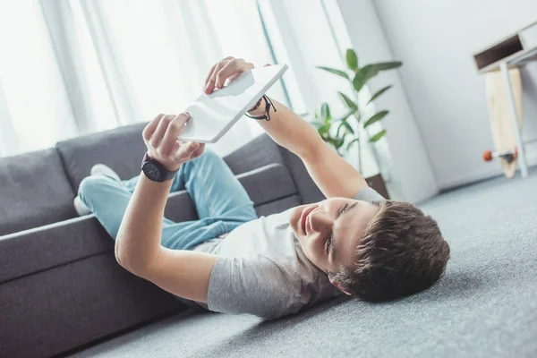 Teenager using digital tablet while lying on floor — Stock Photo