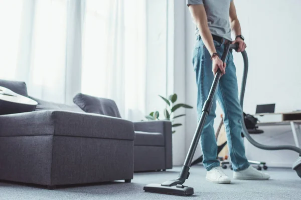 Vista recortada de hombre joven piso de limpieza con aspiradora - foto de stock