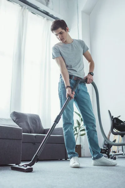 Teenager cleaning floor with vacuum cleaner — Stock Photo