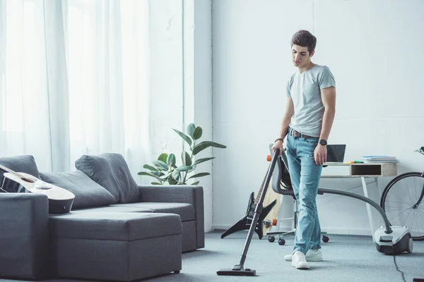 Adolescente menino aspirando chão com aspirador de pó — Fotografia de Stock