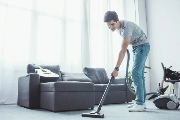 Teenager vacuuming floor in living room with vacuum cleaner — Stock Photo
