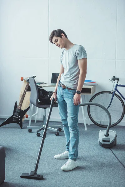 Adolescente menino aspirando chão na sala de estar — Fotografia de Stock