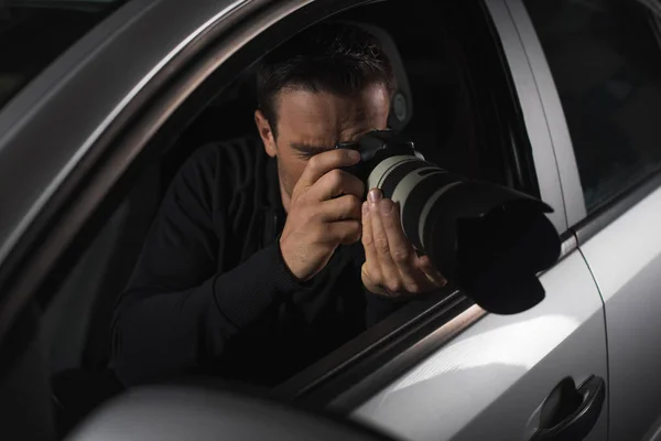 Male paparazzi doing surveillance with camera from his car — Stock Photo