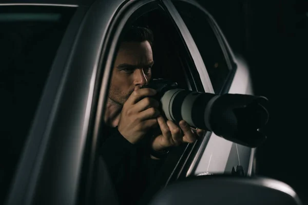 Paparazzi enfocado haciendo vigilancia por cámara desde su coche - foto de stock