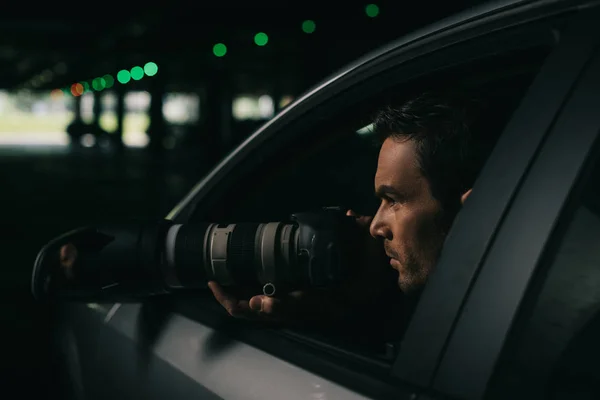 Vue latérale de paparazzi mâle faisant la surveillance avec la caméra de sa voiture — Photo de stock