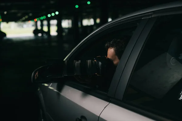 Male paparazzi doing surveillance by camera with object glass from his car — Stock Photo