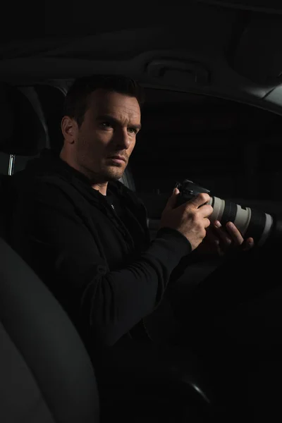 Undercover male agent doing surveillance by camera with lens from car — Stock Photo