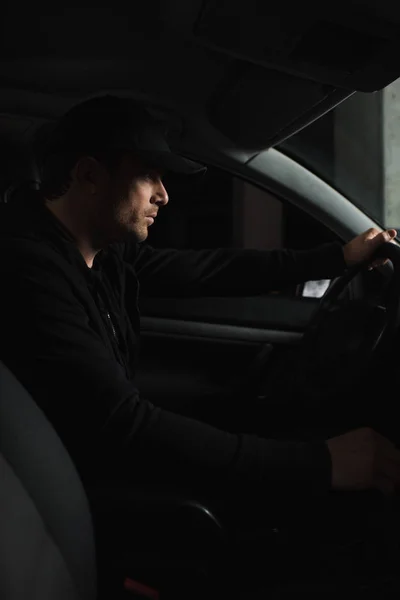 Focused male paparazzi in cap driving car and doing surveillance — Stock Photo