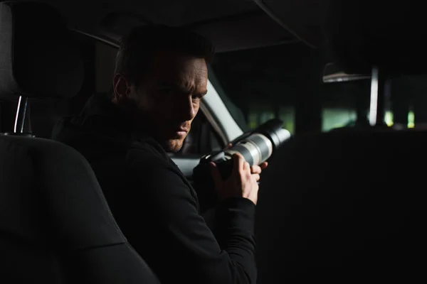 Serious male paparazzi looking at camera while doing surveillance from car — Stock Photo