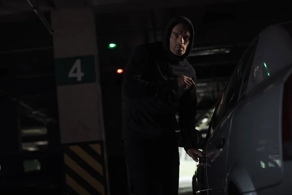 Serious male robber intruding car by picklock — Stock Photo