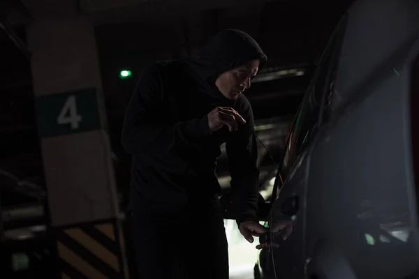 Side view of focused male thief intruding car by picklock — Stock Photo