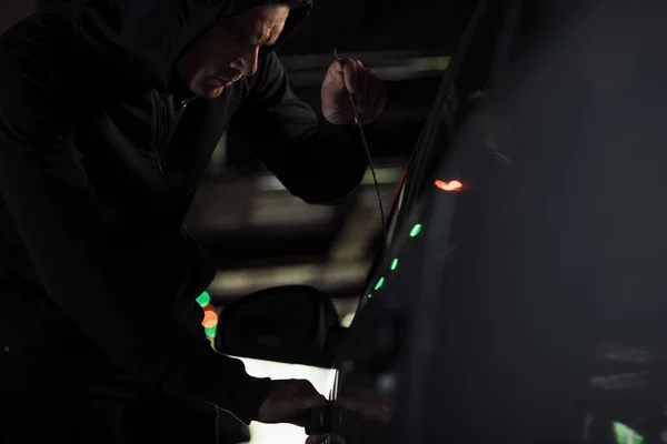 Ladrão masculino com capuz preto intruding carro por picklock — Fotografia de Stock