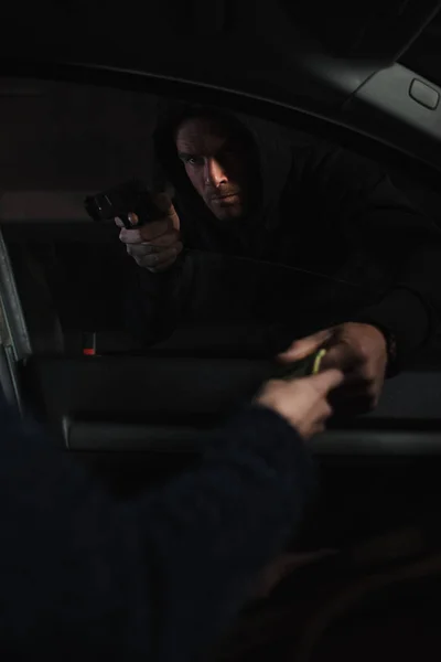 Male mugger aiming by gun on woman while she giving him cash money — Stock Photo