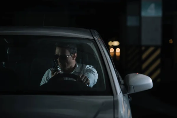 Vue de face de l'agent infiltré masculin dans les lunettes de soleil faisant de la surveillance et utilisant talkie walkie dans la voiture — Photo de stock