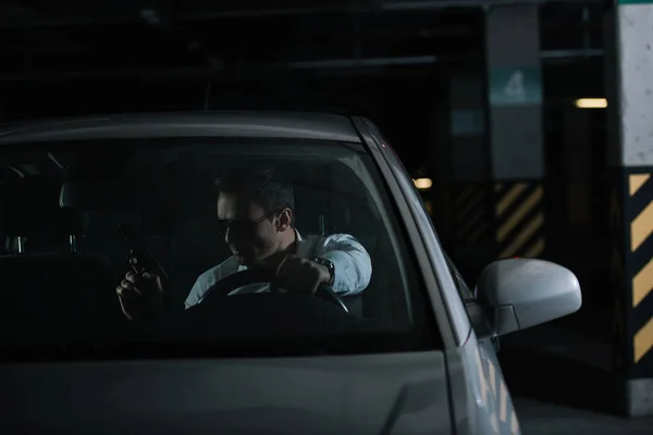 Serious male private detective in sunglasses sitting in car with gun — Stock Photo