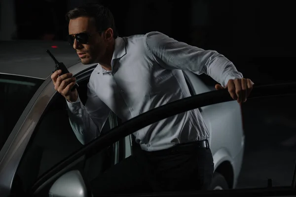Undercover-Agent mit Sonnenbrille benutzt Talkie-Walkie in der Nähe von Auto — Stockfoto