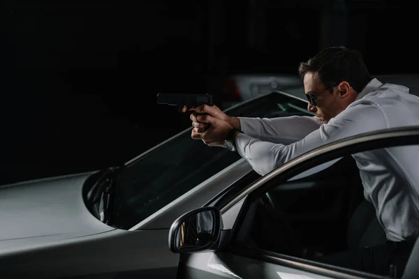 Side view of undercover male agent in sunglasses aiming by gun — Stock Photo