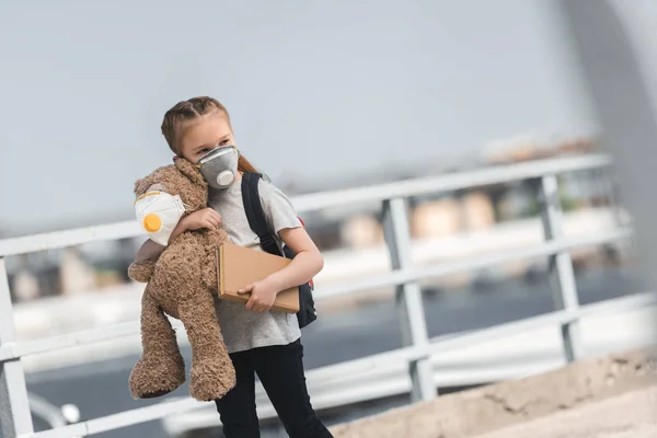 Child in protective mask walking with teddy bear and book on bridge, air pollution concept — Stock Photo