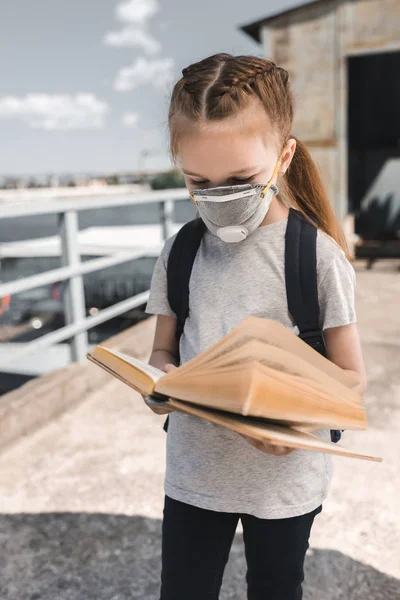 Enfant dans le livre de lecture de masque de protection sur le pont, concept de pollution atmosphérique — Photo de stock