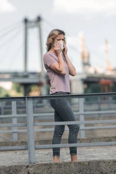 Frau trägt Schutzmaske auf Brücke, Luftverschmutzungskonzept — Stockfoto