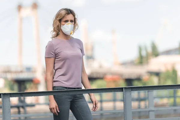 Woman in protective mask standing on bridge and looking away, air pollution concept — Stock Photo