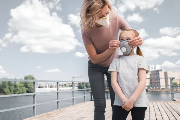 Mutter und Tochter in Schutzmasken auf Brücke, Luftverschmutzungskonzept — Stockfoto