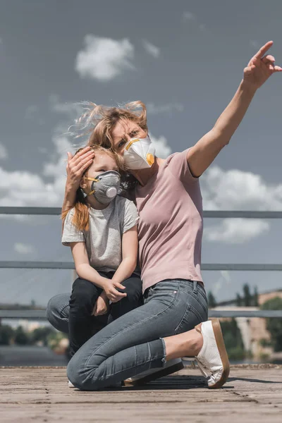 Mutter zeigt Tochter in Schutzmaske auf Brücke, Luftverschmutzungskonzept — Stockfoto