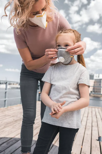 Mother wearing protective mask on daughter for breathing, air pollution concept — Stock Photo