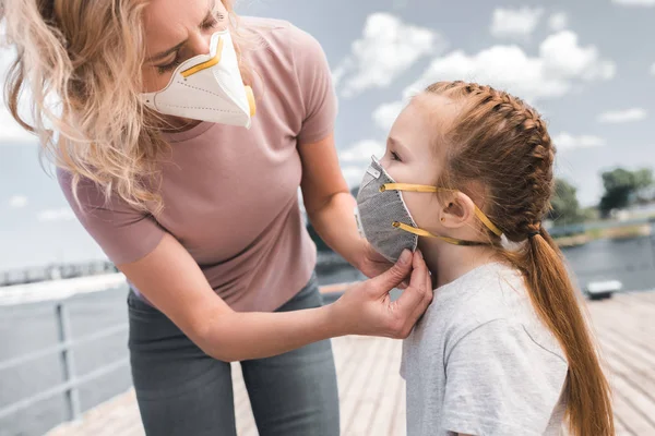 Mère portant un masque de protection sur la fille sur le pont, concept de pollution atmosphérique — Photo de stock