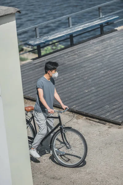 High angle view of asian teen in protective mask standing with bicycle, air pollution concept — Stock Photo