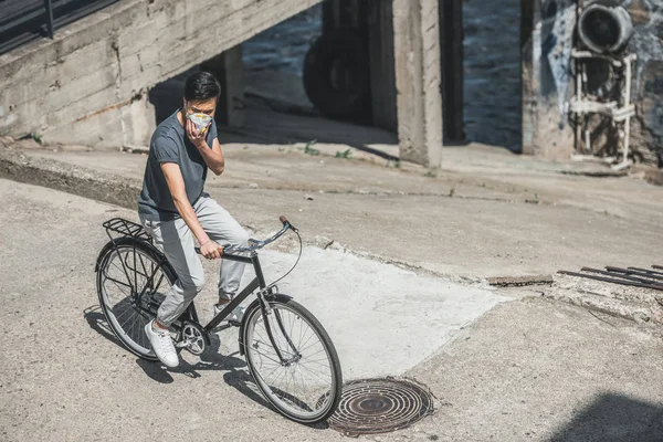 Alto ângulo vista de ásia teen no protetora máscara equitação bicicleta no ponte, ar poluição conceito — Fotografia de Stock