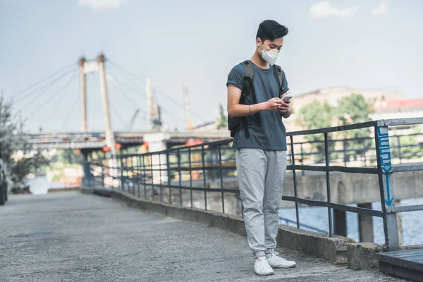 Asiático adolescente en protección máscara usando smartphone, aire contaminación concepto - foto de stock