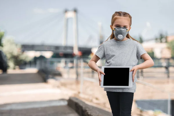 Child in protective mask showing tablet on street, air pollution concept — Stock Photo