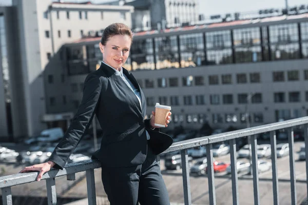 Attraktive Geschäftsfrau steht mit Einweg-Kaffeetasse auf Brücke — Stockfoto