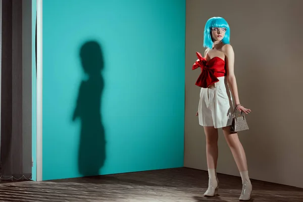 Visão de comprimento total da menina elegante bonita na peruca azul posando e olhando para longe no estúdio — Fotografia de Stock