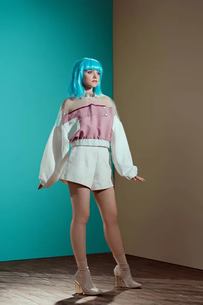 Ganzkörperansicht des modischen weiblichen Modells mit blauer Perücke, das im Studio posiert und wegschaut — Stockfoto