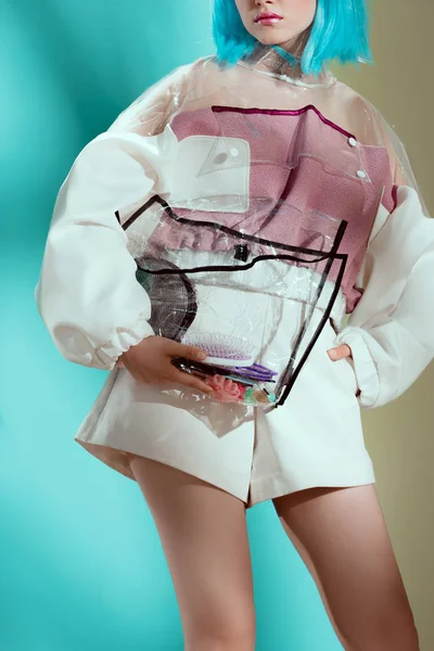 Tiro cortado de menina na moda em peruca azul segurando saco cosmético transparente — Fotografia de Stock