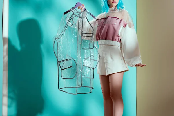 Plan recadré de modèle féminin élégant en perruque bleue tenant imperméable transparent — Photo de stock