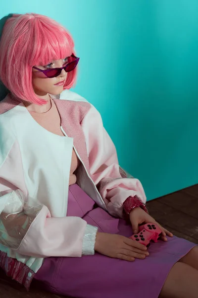 Vista de ángulo alto de chica bastante elegante en peluca rosa sosteniendo joystick, sentado en el suelo y mirando hacia otro lado - foto de stock
