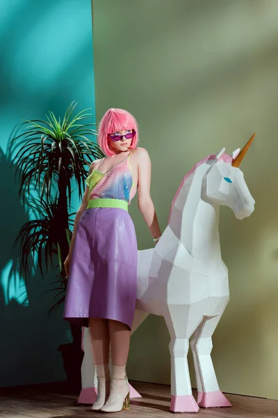 Fashionable beautiful girl in pink wig leaning at unicorn — Stock Photo