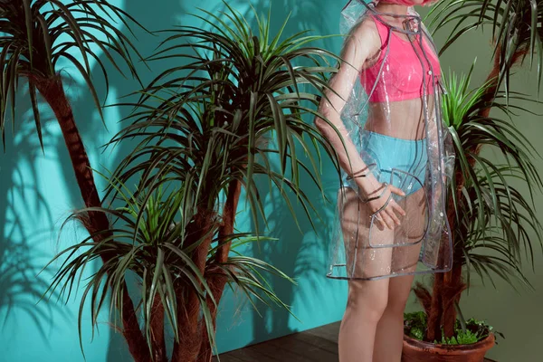 Cropped shot of female model in transparent raincoat posing in studio — Stock Photo