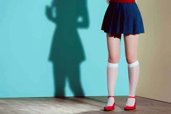 Cropped shot of girl in red shoes, stockings and skirt posing in studio — Stock Photo