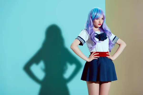 Attractive stylish girl in bright wig and skirt standing with hands on waist and looking away in studio — Stock Photo