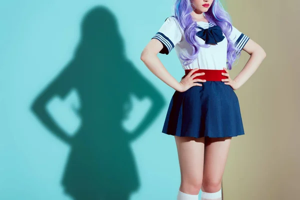 Обрезанный снимок стильной девушки в ярком парике и юбке стоя с руками на талии в студии — стоковое фото