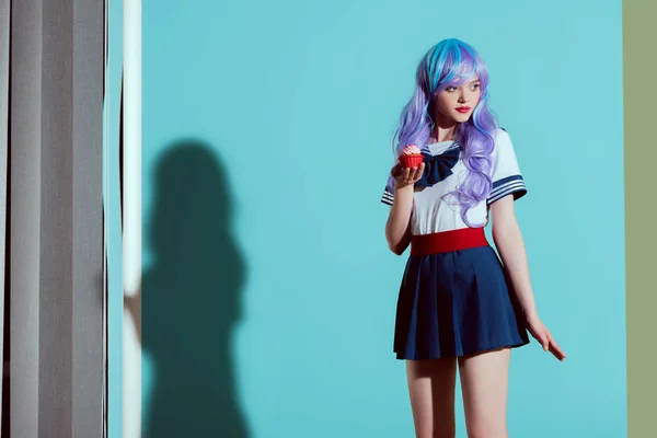 Stylisches Mädchen mit heller Perücke hält Cupcake in der Hand und schaut im Atelier weg — Stockfoto